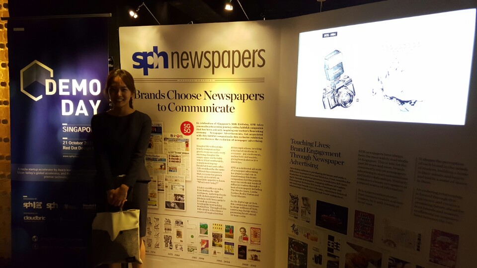 Woman in blue dress standing next to large newspaper banners inside a museum