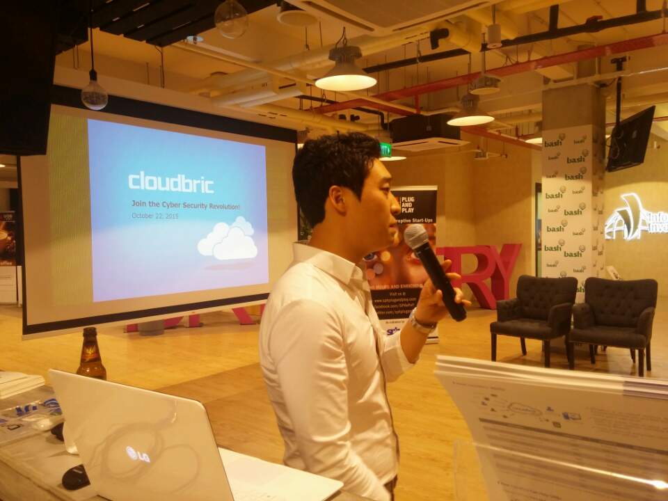 Man holding microphone with white shirt and the Cloudbric logo in the background