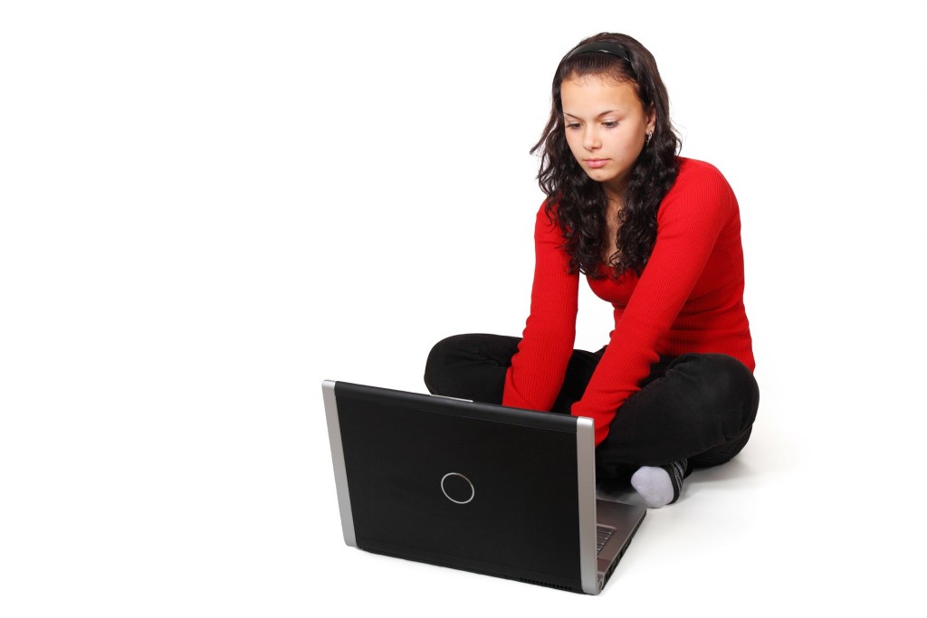 A woman uses a laptop on the floor. 