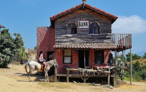 An old-time bank in the Wild West with a woman on horseback.