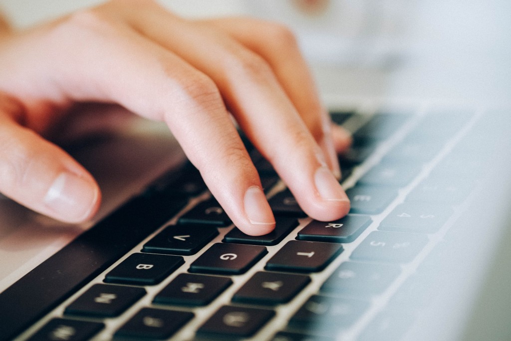 Hand using a laptop to type words on the black keyboard