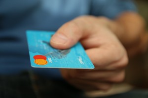 Hand extending light blue credit card to viewer
